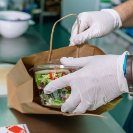 A healthy salad is packed into a paper bag in a kitchen